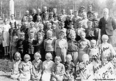 Hiitolan Pukinniemen pysäkkikylän koululaisia 1937. Opettaja Aili ja Reino Kokkonen.
